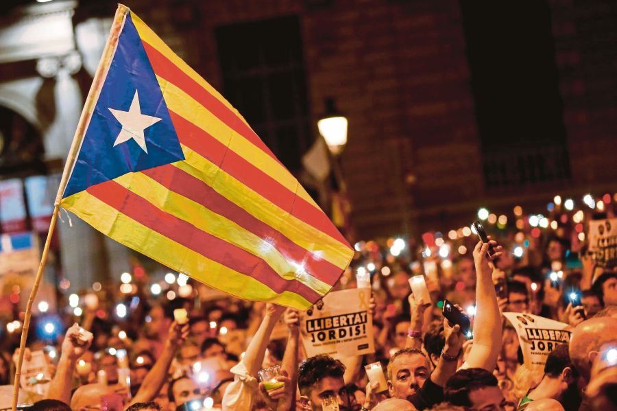 People hold candles and a Catalan pro-independence ‘Estelada’ flag during a demonstration in Barcelona against the arrest of two Catalan separatist leaders on Tuesday.Catalonia braced for protests after a judge ordered the detention of the duo, further inflaming tensions in the crisis over the Spanish region’s chaotic independence referendum. (AFP PIC)
