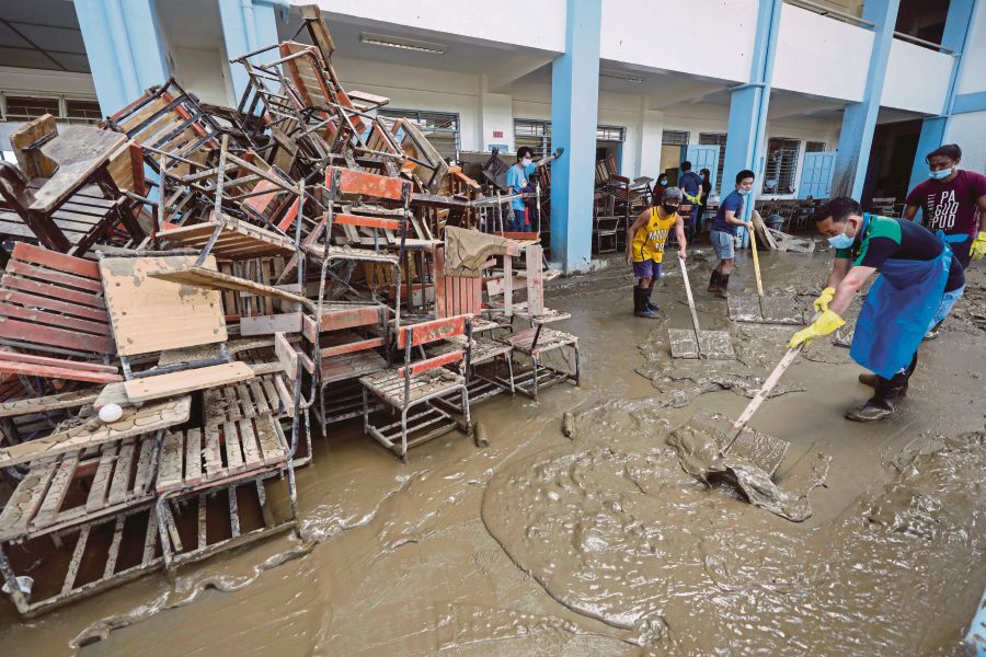 Residents and staff on Wednesday cleaning a muddied school at a riverside community affected by flood in Marikina City, Metro Manila. EPA PIC 