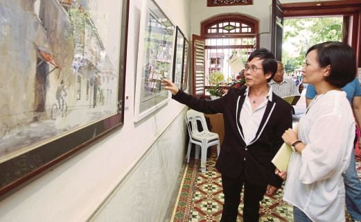  Koay Shao Peng (left) explaining a painting to a visitor at the launch of his exhibition at Galeri Seni Mutiara.