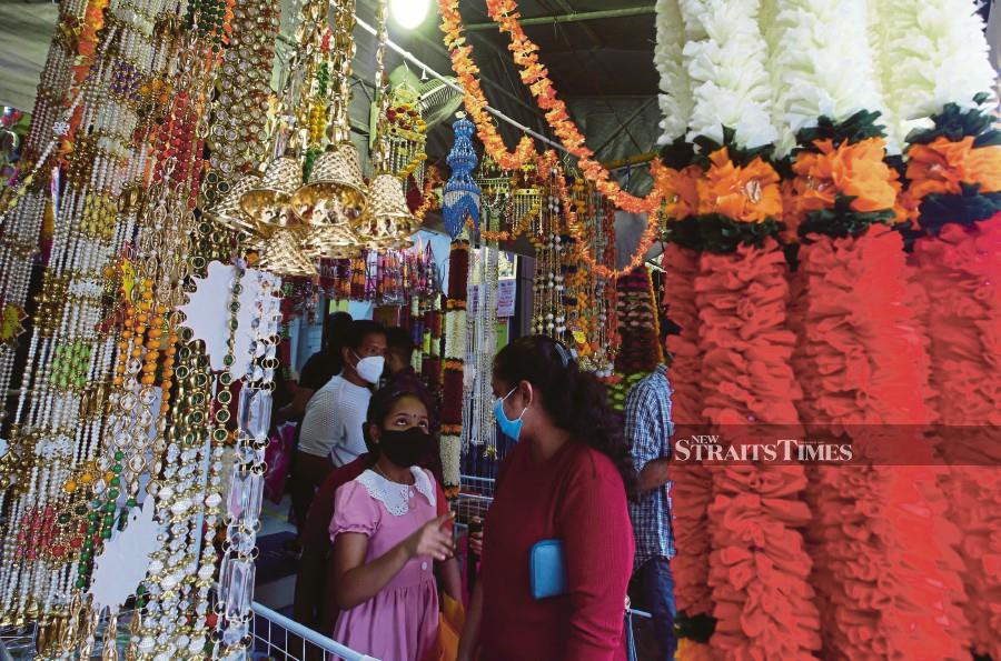 Customers walking past flower garlands and decorations hung up at stores  in preparation for Deepavali at ‘Little India’ in George Town, Penang, on Saturday. -NSTP/DANIAL SAAD