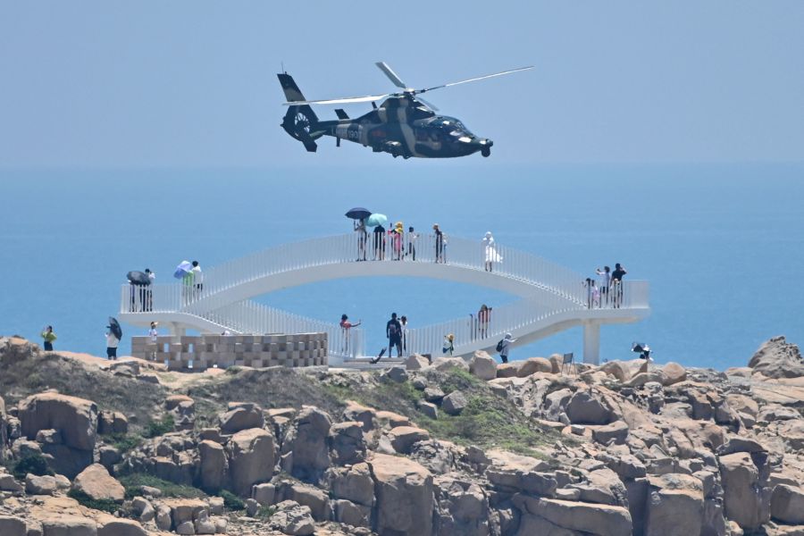 Tourists look on as a Chinese military helicopter flies past Pingtan island, one of mainland China's closest point from Taiwan, in Fujian province on August 4, 2022, ahead of massive military drills off Taiwan following US House Speaker Nancy Pelosi's visit to the self-ruled island. -AFP file pic