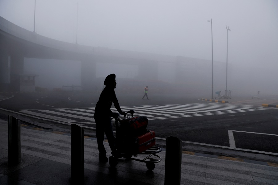 A man is seen with his luggage cart amidst heavy fog at the Indira Gandhi International Airport in New Delhi, India. (REUTERS/Anushree Fadnavis)