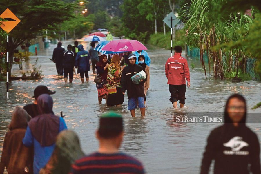 Telok Kalong residents in Kemaman heading to the nearest flood relief centre after their homes were flooded yesterday. -- NSTP/ GHAZALI KORI