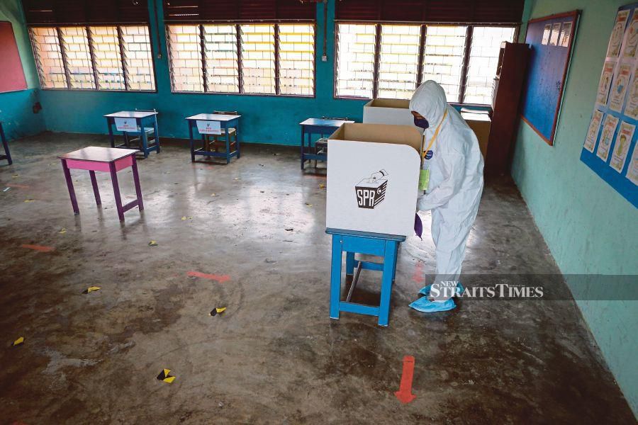  A sanitation worker in full protective equipment disinfecting a polling station at SK Tanjung Bidara yesterday. -NSTP/ASYRAF HAMZAH 