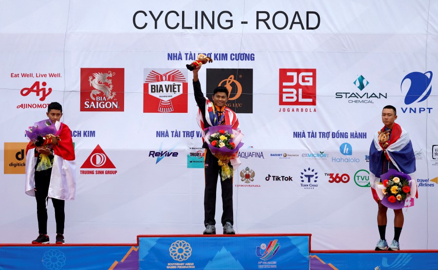 Malaysia's Nur Aiman Zariff celebrates on the podium after winning gold in the men's individual road race alongside silver medallist Indonesia's Aiman Cahyadi and bronze medallist Thailand's Sarawut Sirironnachai - REUTERS PIC