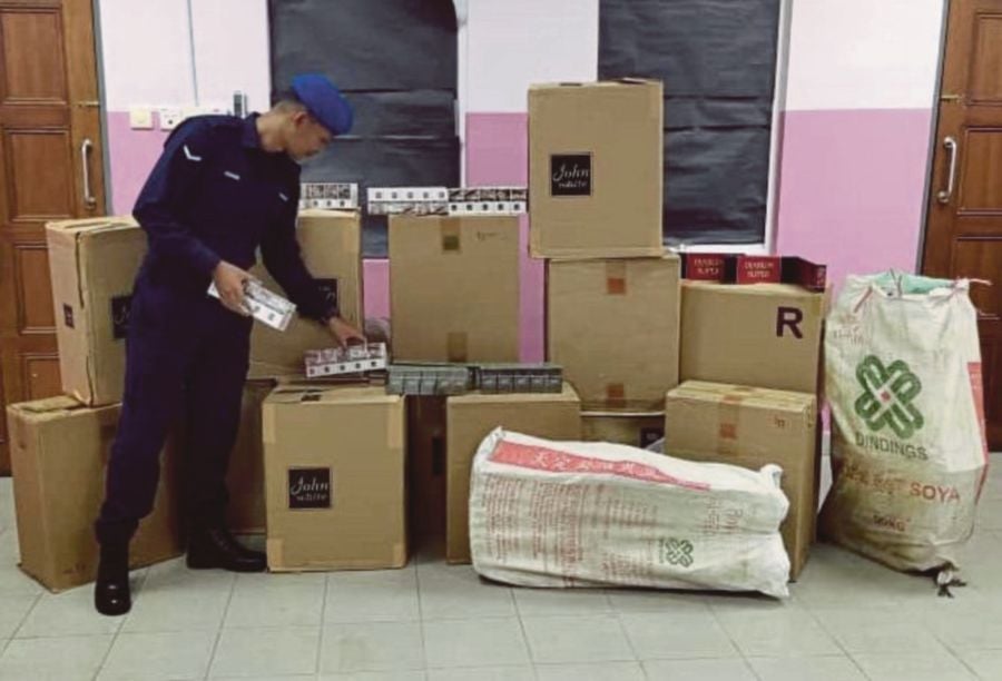 A marine police officer checking seized contraband cigarettes in Port Klang in August. -NSTP/File pic