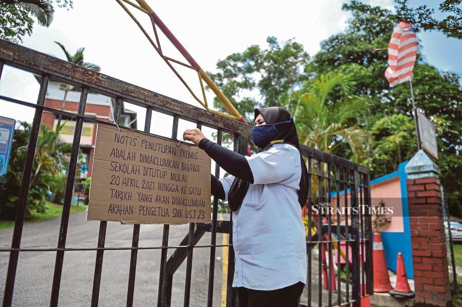 A SMK USJ 23 staff member putting up a closure sign on the school’s gate in Subang Jaya yesterday. - BERNAMA pic