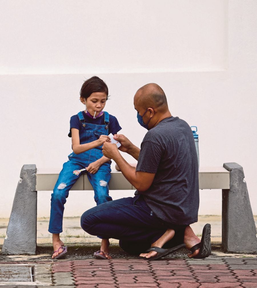 Jefri Akhbar, 47, calming his daughter Qaisara Ardini, 7,  after she received a dose of a Covid-19 vaccine at the Padang Hiliran People’s Housing Project multipurpose hall vaccination centre in Kuala Terengganu yesterday. -NSTP/GHAZALI KORI