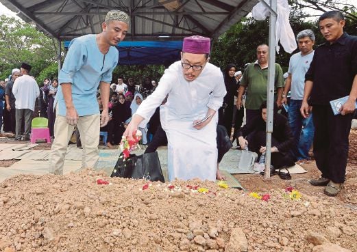 Ismail Ani sprinkling flower petals on the grave of his father, Tan Sri Ani Arope, in Shah Alam yesterday. Pic by Mohd Asri Saifuddin Mamat