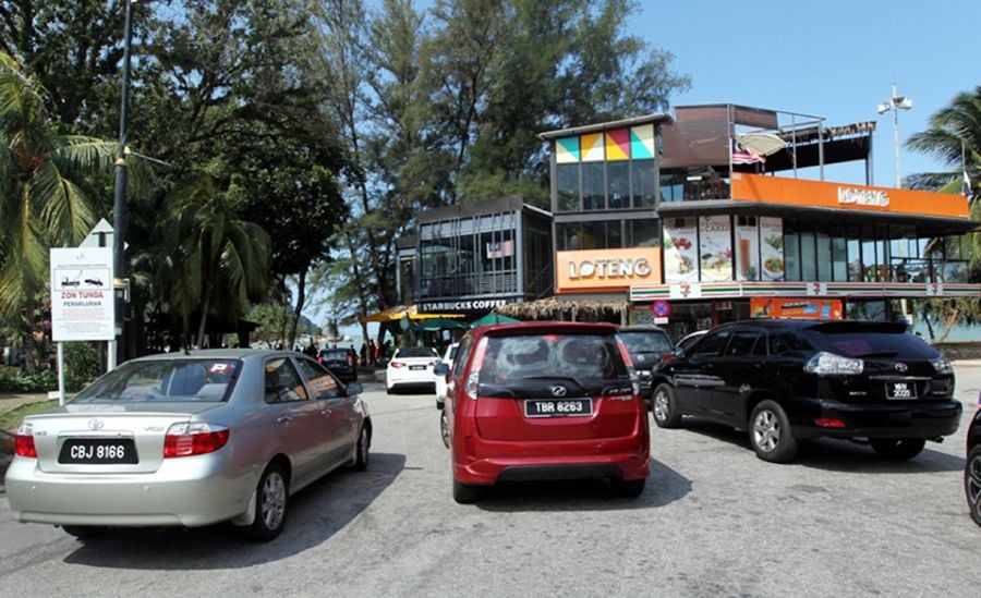 Vehicles parked illegally near the entrance to the Teluk Cempedak beach in Kuantan.