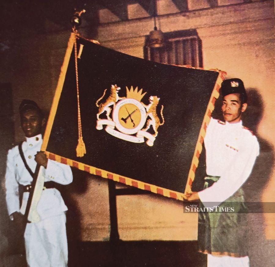 Two soldiers holding up a flag with the badge of the Malay Regiment, which was designed by Major George McIllree Stanton Bruce and Captain K.G. Exham. - Pix by Alan Teh Leam Seng