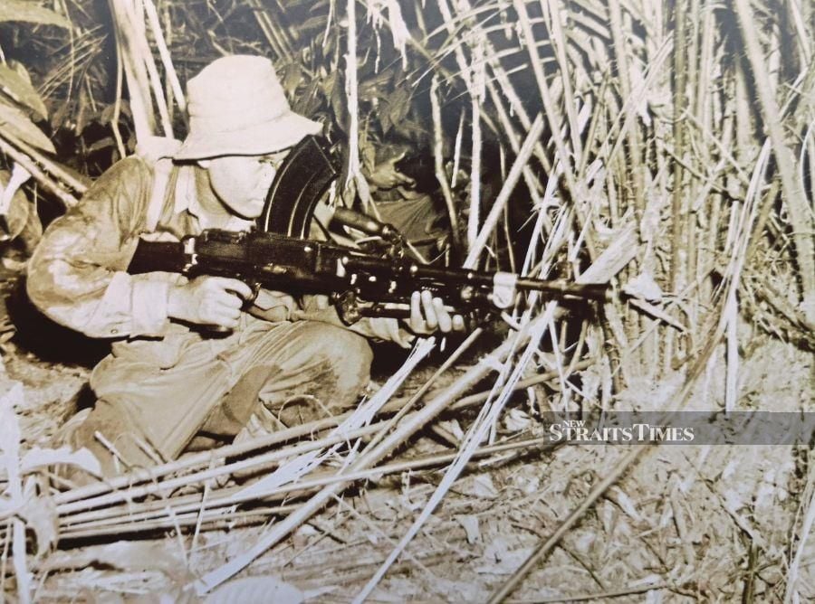 A soldier with the Malay Regiment taking aim with his firearm in a forest. - Pix by Alan Teh Leam Seng