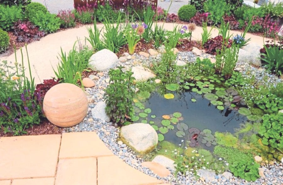 A rock garden with a pond, pebbled border and stone walkway