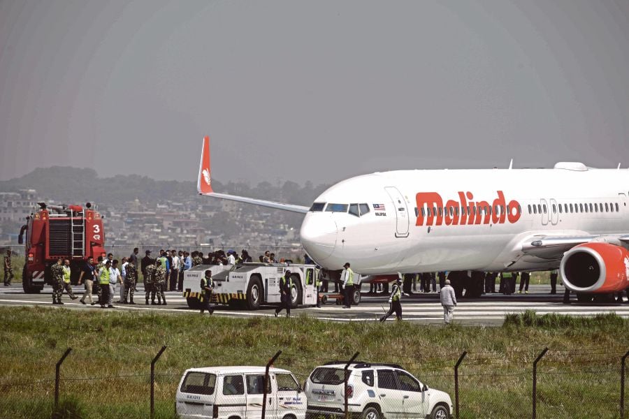 Nepali workers try to bring a Malaysian airliner back onto the runway at the international airport in Kathmandu on April 19, 2018, after it skidded off the runway following an aborted take-off.Kathmandu airport was closed April 20 after a Malaysian jet with 139 people on board aborted its takeoff and skidded off the runway, officials said. Nobody was hurt in the incident but incoming flights to the Nepali capital were diverted while authorities tried to move the Malindo Airlines Boeing 737, which was stuck in mud. AFP PHOTO 