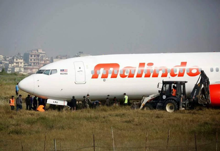  Nepali workers try to bring a Malaysian airliner back onto the runway at the international airport in Kathmandu on April 19, 2018, after it skidded off the runway following an aborted take-off.