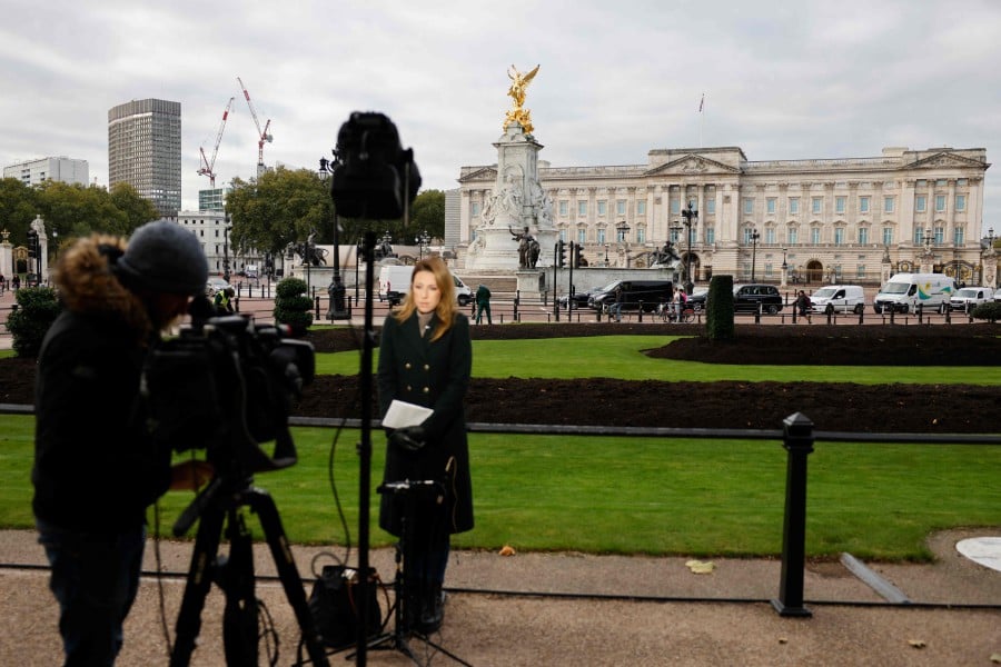 A news crew reports from outside the Buckingham Palace in London on October 22, 2021. - Queen Elizabeth II spent a night in hospital for tests after being forced to cancel a visit to Northern Ireland this week, Buckingham Palace said. -AFP PIC