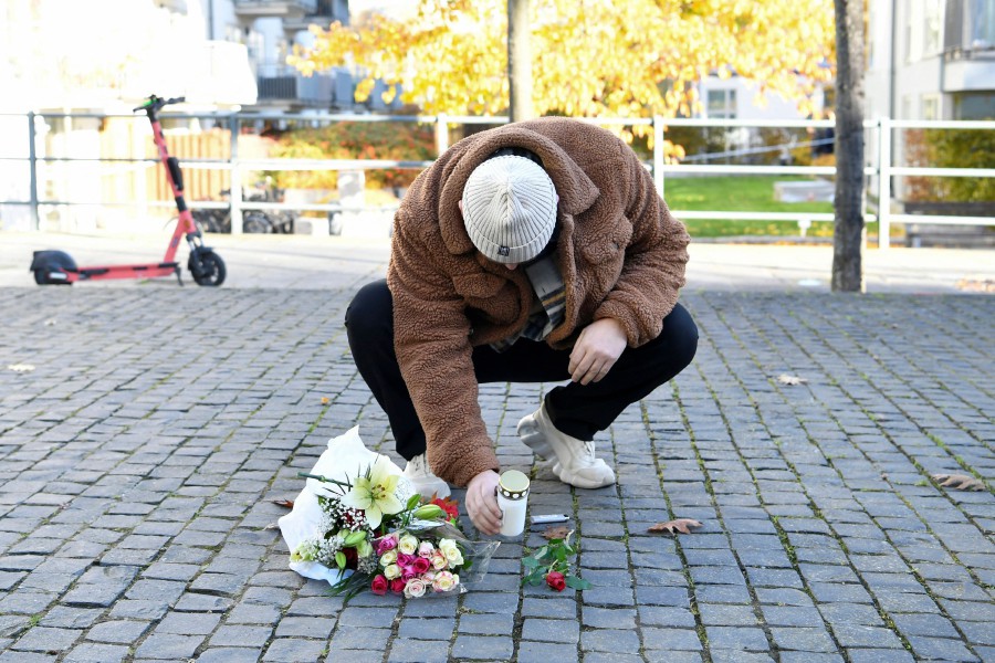 A man places flowers and candles near a crime scene in the Hammarby Sjostad district in Stockholm on October 22, 2021 after a person believed to be the Swedish rap artist Einar, officially named Nils Kurt Erik Einar Gronberg, was shot to death late on October 21. -AFP PIC