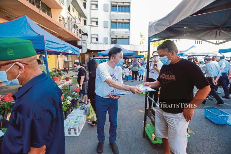  Independent  Api-Api candidate Ng Chun Sua handing out brochures at Gaya Street Sunday Market in Kota Kinabalu on Sunday.   -NSTP/ASWADI ALIAS