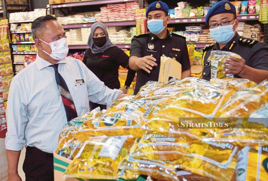 Johor Ministry of Domestic Trade and Consumer Affairs director Mohd Hairul Anuar Bohro (left) and state enforcement chief Mohd Hanizam Kechek (right) checking the price of subsidised cooking oil at a supermarket in Johor Baru on Wednesday. -NSTP/ZAIN AHMED