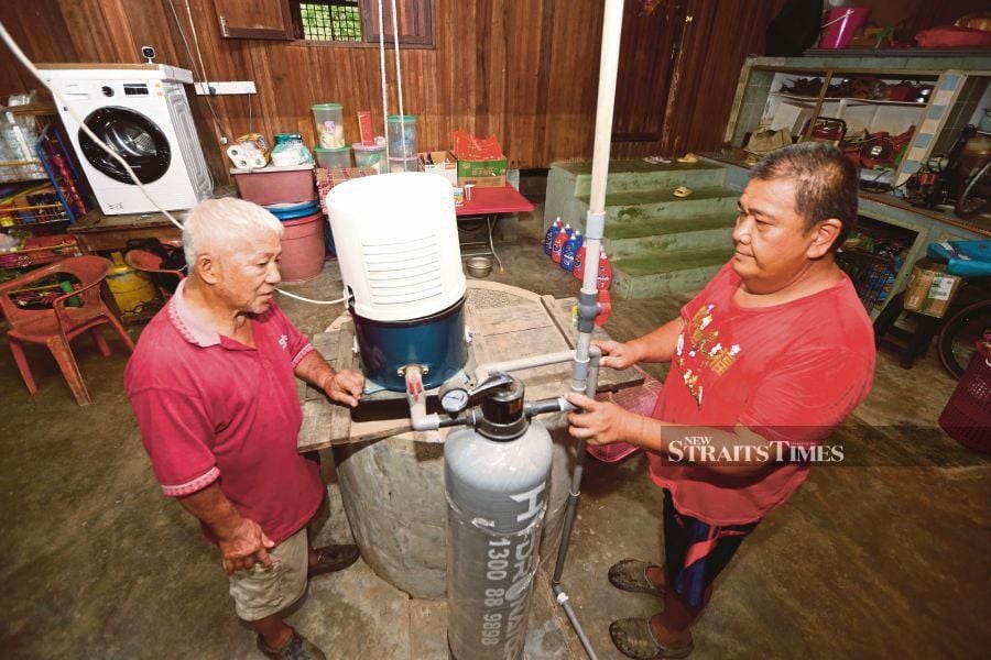 Ang Boon Kek (right) showing the tube well that he has installed to his friend, Owe Cheng Huai, at his home in Kampung Sakar Sungai in Pasir Mas, Kelantan. -NSTP/NIK ABDULLAH NIK OMAR