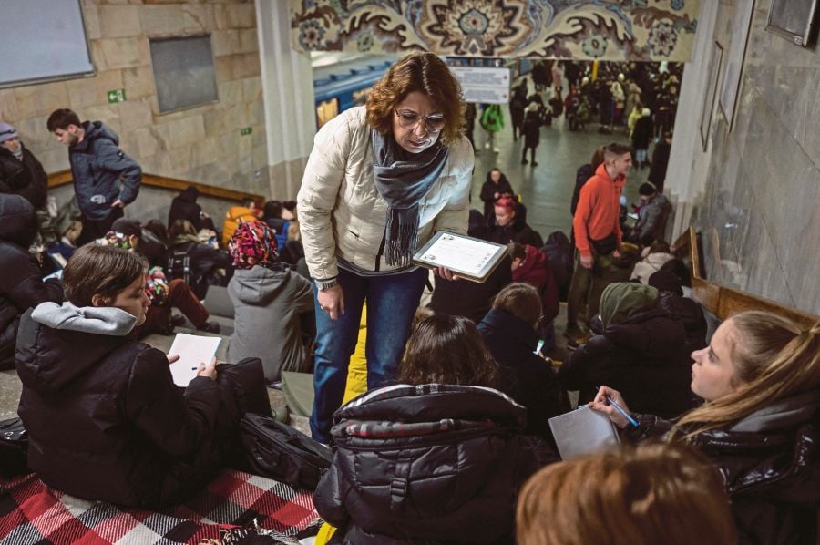 A teacher conducting a lesson for school students as they take shelter inside a metro station during Russian missile attacks in Kyiv on Feb 10.- REUTERS PIC