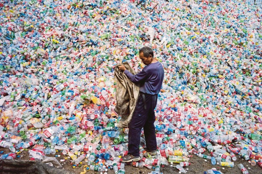 A Chinese labourer sorting out plastic bottles for recycling in Dong Xiao Kou village in the outskirts of Beijing. FILE PIC