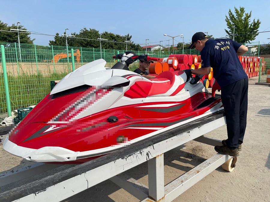 An undated handout photo made available by Korea Coast Guard shows two Coast Guard personnel looking at a jet ski in Incheon, after the Coast Guard confirmed it had arrested a Chinese man who "attempted to smuggle into" the western port city of Incheon last week on the jet ski from China's Shandon. A man who crossed from China to South Korea on a jet ski on a 300 plus kilometre voyage is an asylum seeking human rights activist, his representative told AFP, who has been an outspoken critic of Chinese leader Xi Jinping and was jailed for it. -AFP/KOREA COAST GUARD