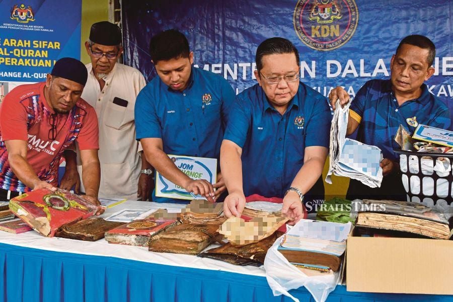 KDN Enforcement and Control Division secretary, Nik Yusaimi Yussof (fourth from left), inspects damaged Qurans due to flooding to be replaced for residents during the 'Let's Exchange Quran' programme and flood victims' solidarity event at Masjid Taman Maka Kampung Jakar, Alor Pasir, Pasir Mas. Pic by NSTP/Nik Abdullah Nik Omar