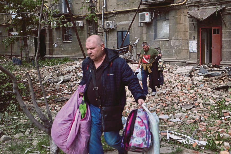 People taking their belongings out of a residential building damaged as a result of a missile attack in Dnipro on April 19, 2024.- AFP PIC 