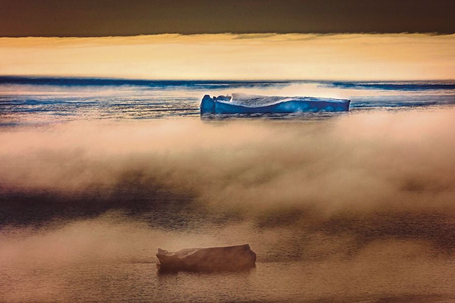 Icebergs floating in fog-covered Baffin Bay near Pituffik, Greenland in July, 2022. Some economists are accused of underestimating the effects of climate change to the economy. - AFP PIC 