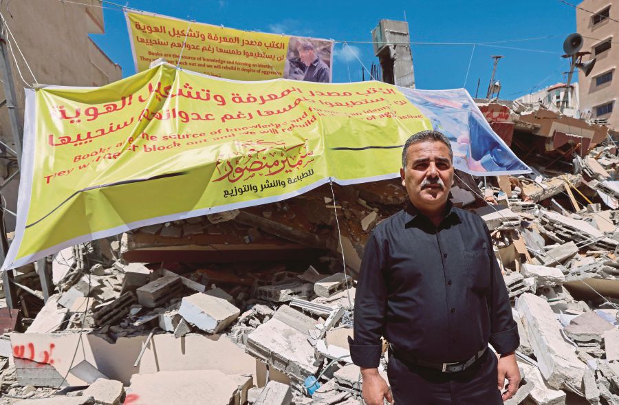 A Palestinian bookstore owner standing on the rubble of his shop after it was destroyed by Israeli airstrikes, in Gaza City on Saturday. -AFP pic 
