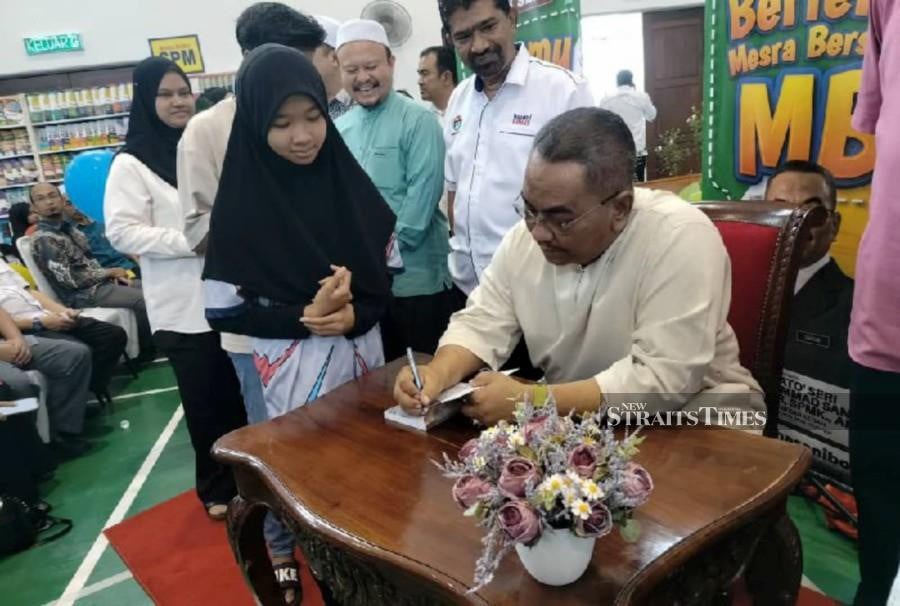 Kedah Menteri Besar Datuk Seri Muhammad Sanusi Md Nor signing autographs on novels of his autobiography at a book fair in Pokok Sena here today. NSTP/AHMAD MUKHSEIN MUKHTAR