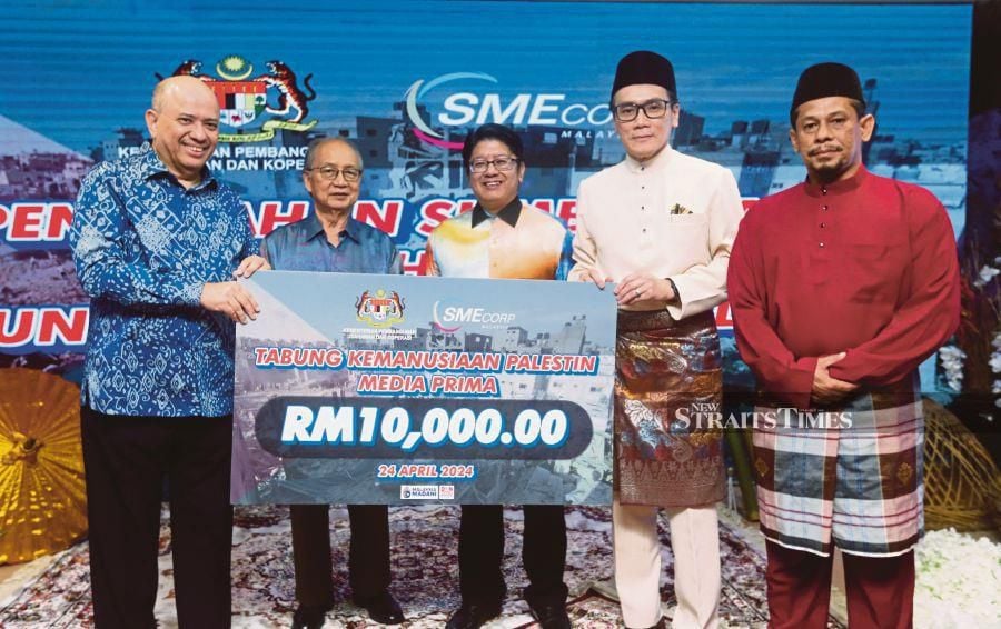  SME Corp chief executive officer Rizal Nainy (second from right) handing over a RM10,000 mock cheque to the Media Prima Palestinian Humanitarian Fund to Media Prima Bhd group chairman Datuk Seri Dr Syed Hussian Aljunid (left) with Entrepreneur Development and Cooperatives Minister Datuk Ewon Benedick (third from right) looks on. NSTP/ROHANIS SHUKRI