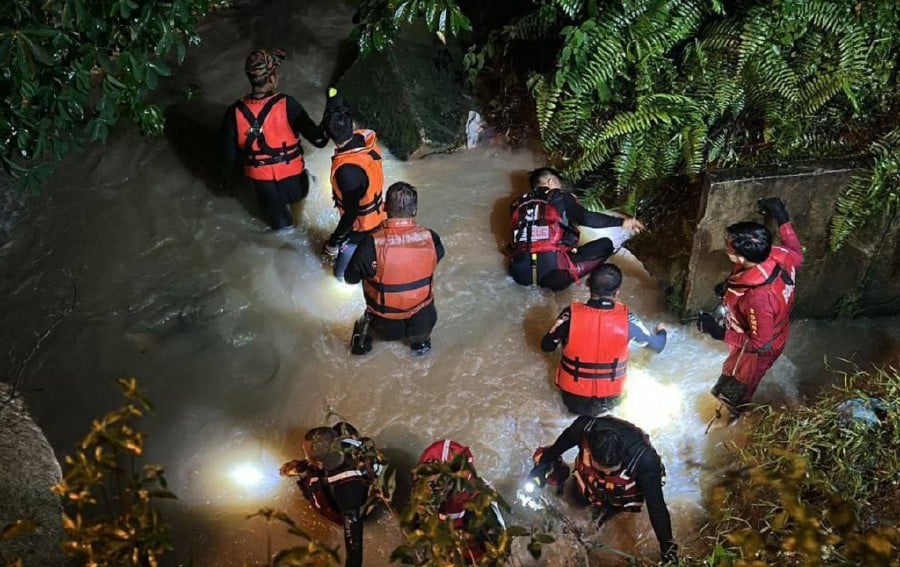 Firemen looking for the missing 5-year-old boy who fell into a water-filled ditch at Kampung Sungai Tiram in Johor.-Courtesy pic