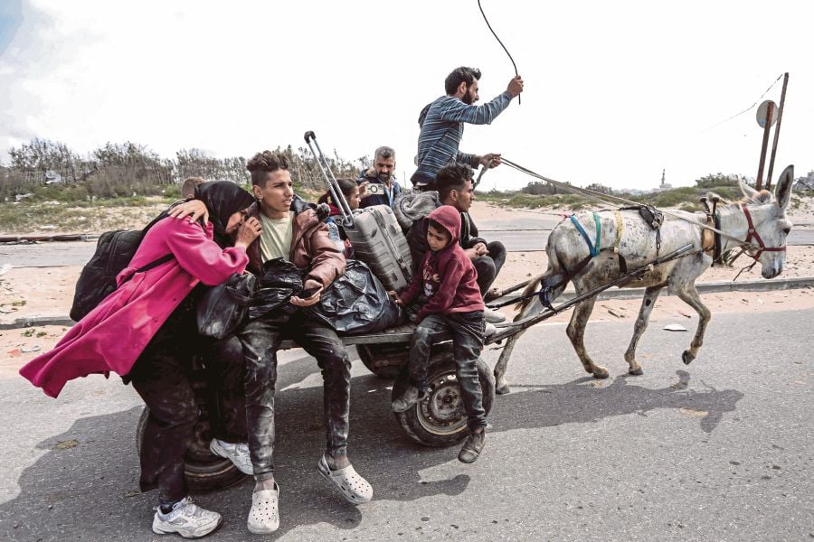  Palestinians who fled from the vicinity of Gaza City’s Al-Shifa Hospital on a donkey-drawn cart arriving at a refugee camp, in the Gaza Strip on March 18. AFP PIC