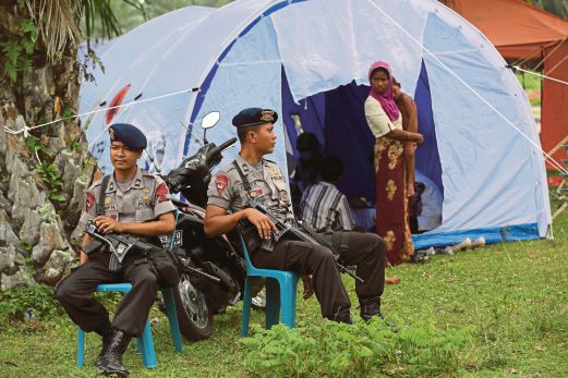 Police officers stand guard near a temporary shelter in Langsa, Aceh province, Indonesia, on Friday. Thousands of refugees and migrants have come ashore in Malaysia,Indonesia and Thailand, about half of them Rohingyas and the rest from Bangladesh. There is no quick and easy solution to this heart-wrenching problem. AP pic