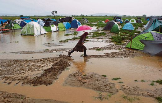  A woman walking in a flooded field at a makeshift camp for refugees in the Greek-Macedonian border near the village of Idomeni, Greece, recently. Reuters pic