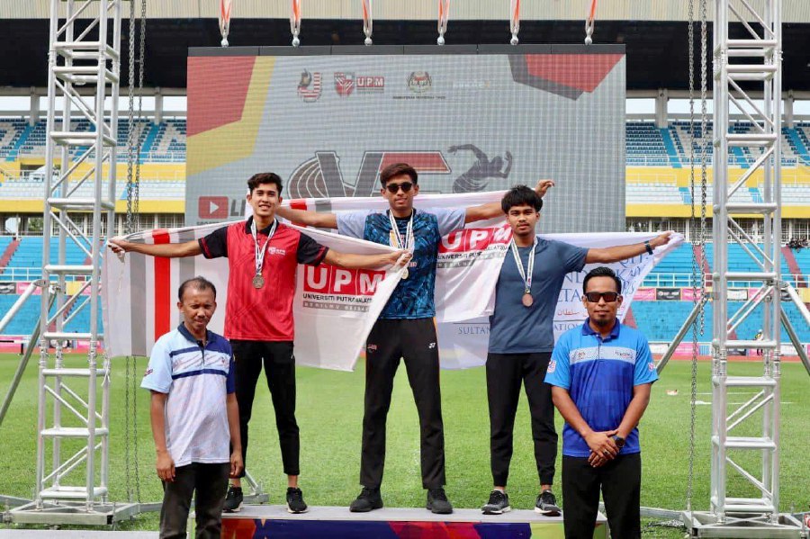 Ruslem Zikry Putra Roseli (centre) celebrates on the podium after winning the men’s 400m hurdles gold medal in the Higher Learning Institution Athletics Championships at Darulmakmur Stadium, Kuantan, today.