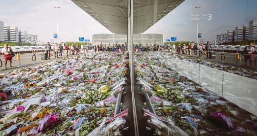 epa04331344 Travellers stop to view the thousands of floral tributes placed in memory of the victims of Malaysian Airlines flight MH17 at Schiphol Airport, near Amsterdam, the Netherlands, 26 July 2014. Flight MH17 with more than 280 passengers, including 194 Dutch passengers on board, crashed in eastern Ukraine on 17 July. EPA/Bart MaatBart Maat
