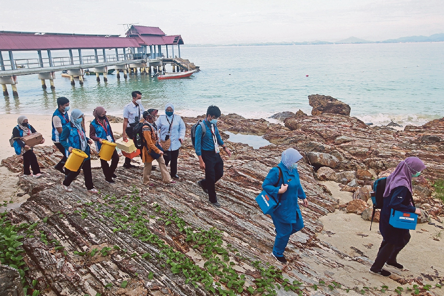 Frontliners from the Marang district health office carrying equipment needed during a vaccination drive in Pulau Kapas where they vaccinated resort and boat operators on the island. Pic by Ghazali Kori