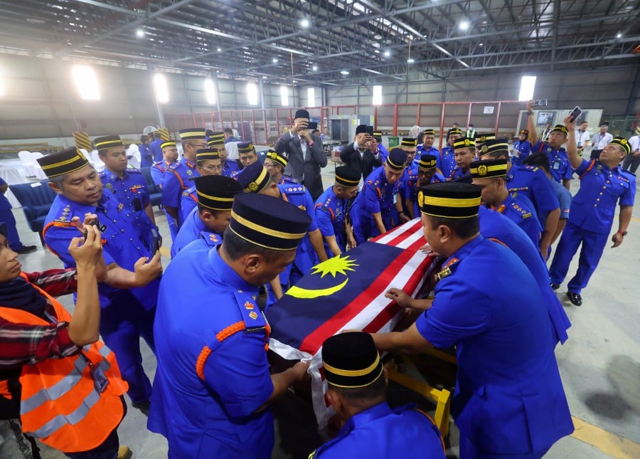 Civil Defence Force personnel receiving the body of Lieutenant Colonel Awang Askandar Ampuan Yaacub at the Kuala Lumpur International Airport cargo complex yesterday. BERNAMA PIC 