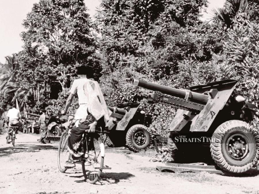 A man cycling past a 105 Field Battery of the Royal Australian Artillery in Kedah on July 3, 1957, set up after the regiment came into contact with communists. -NSTP/File pic