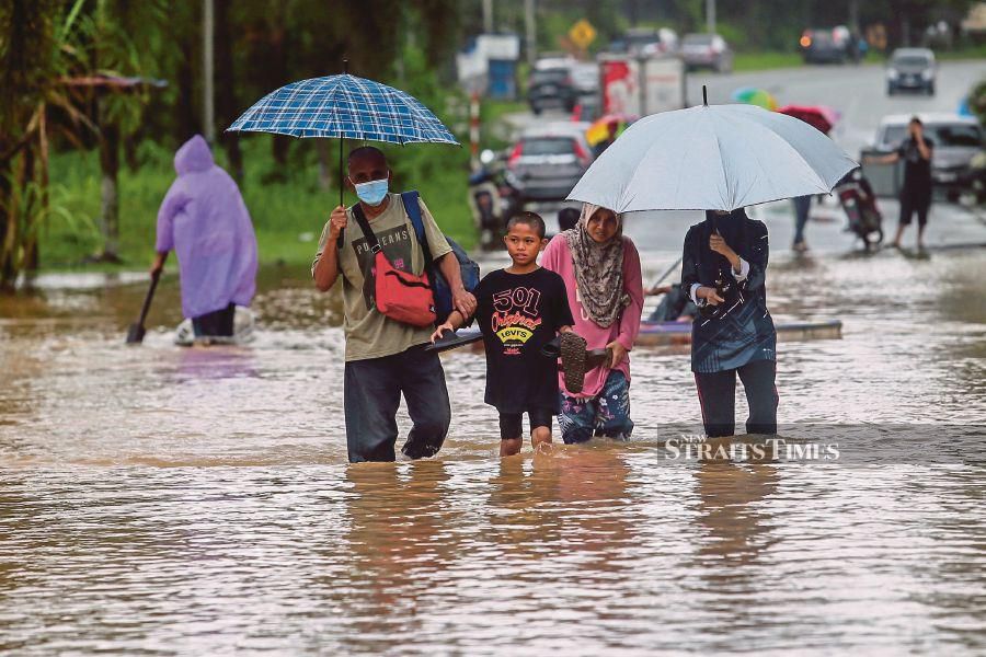 People braving floodwaters in Hulu Terengganu yesterday. PIC BY GHAZALI KORI