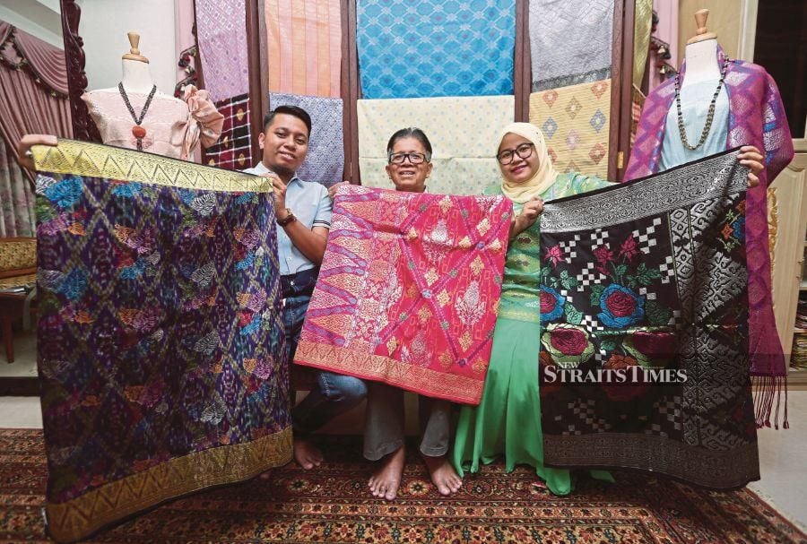 Songket entrepreneur Wan Manang Wan Awang (centre) and his children, Wan Benyamin (left) and Wan Nadila, displaying their Terengganu songket products at their home in Kuala Terengganu on Oct 17. PIX BY GHAZALI KORI 