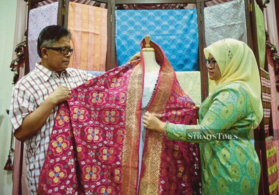  Wan Manang (left) and Wan Nadila showing a piece of songket fabric. 