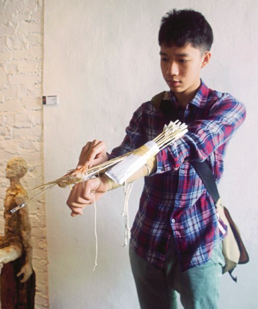 Brendan Beh Wye Hsien demonstrating how his crossbow, made from discarded materials. 