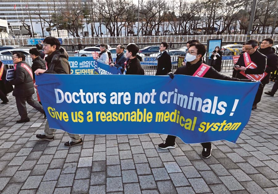 Doctors carry a banner reading "Doctors are not criminals!" as they march toward the Presidential Office during a rally to protest against the government?s plan to raise the annual enrolment quota at medical schools, in Seoul. (Photo by Jung Yeon-je / AFP)
