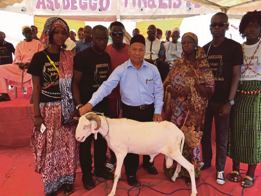 Noor Habibullah Md Nasir (in songkok), the personal assistant to the Malaysian ambassador to Senegal, holding the sacrificial goat at the handing-over ceremony.