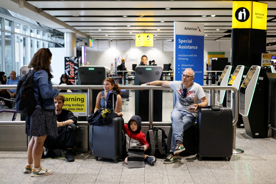 A family waits as their flight delays as Britain's National Air Traffic Service (NATS) restricts UK air traffic due to a technical issue causing delays, in London, Britain. -REUTERS/Hollie Adams