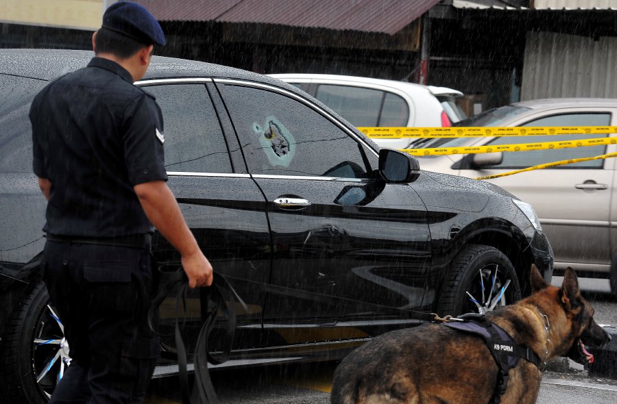 A K9 unit sweeps through the crime scene after a mobile phone seller was injured in a drive by shooting at Jalan Sentosa on May 26. Bernama pic.